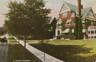 Picture of a three storey brick house with awnings on windows on treed street. 