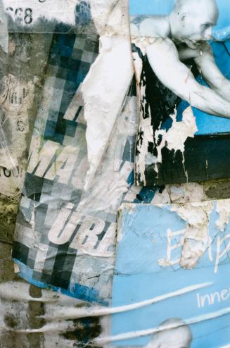 A close-up photograph of a surface covered in posters and graffiti. Portions of posters, some o ...