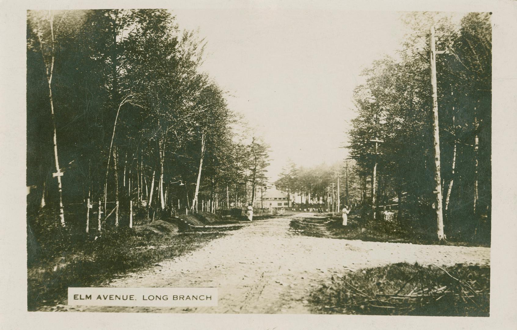 Black and white photograph of a summer cottage at then end of a road in the bush.