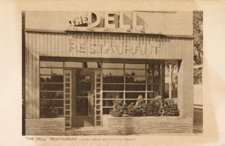 Sepia-toned photo postcard depicting the front of a restaurant with caption at the bottom of th…