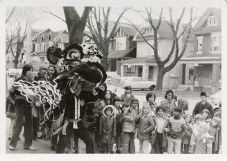 Photo of children with Chinese dragon on street. 