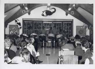 Photo of crowd seated watching steel band. 