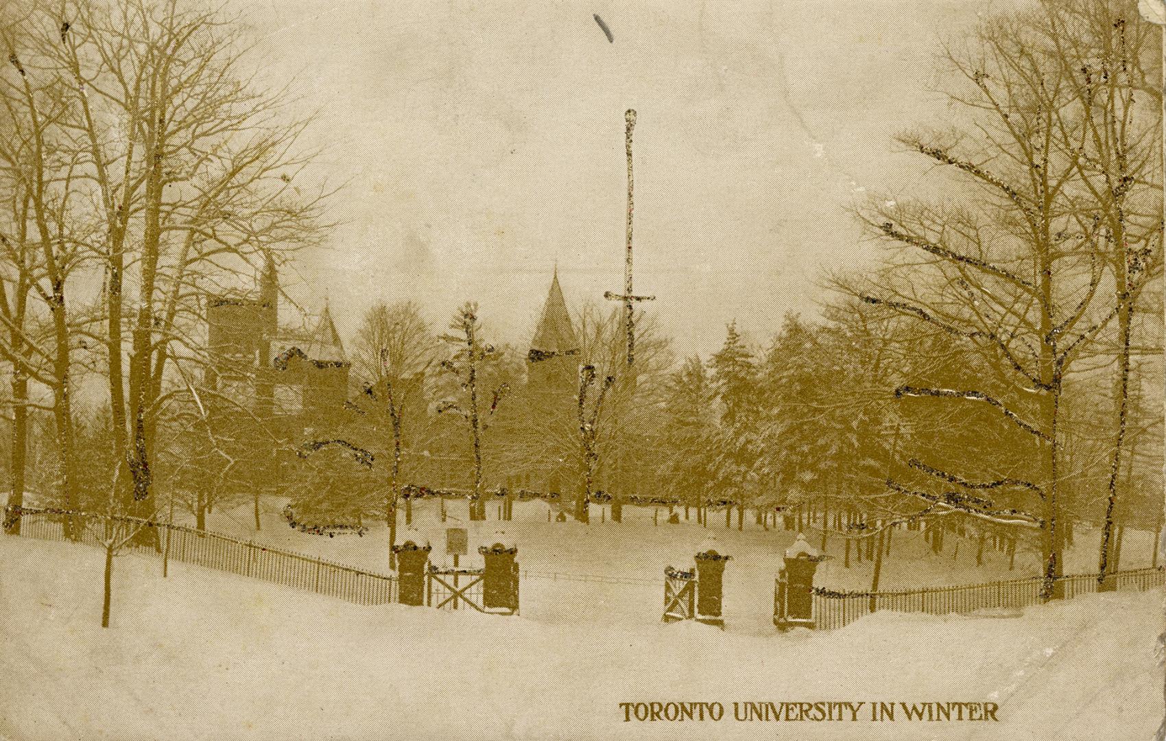 Brick gates on a roadway in front of trees and a large collegiate building in winter. 