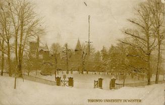 Brick gates on a roadway in front of trees and a large collegiate building in winter. 