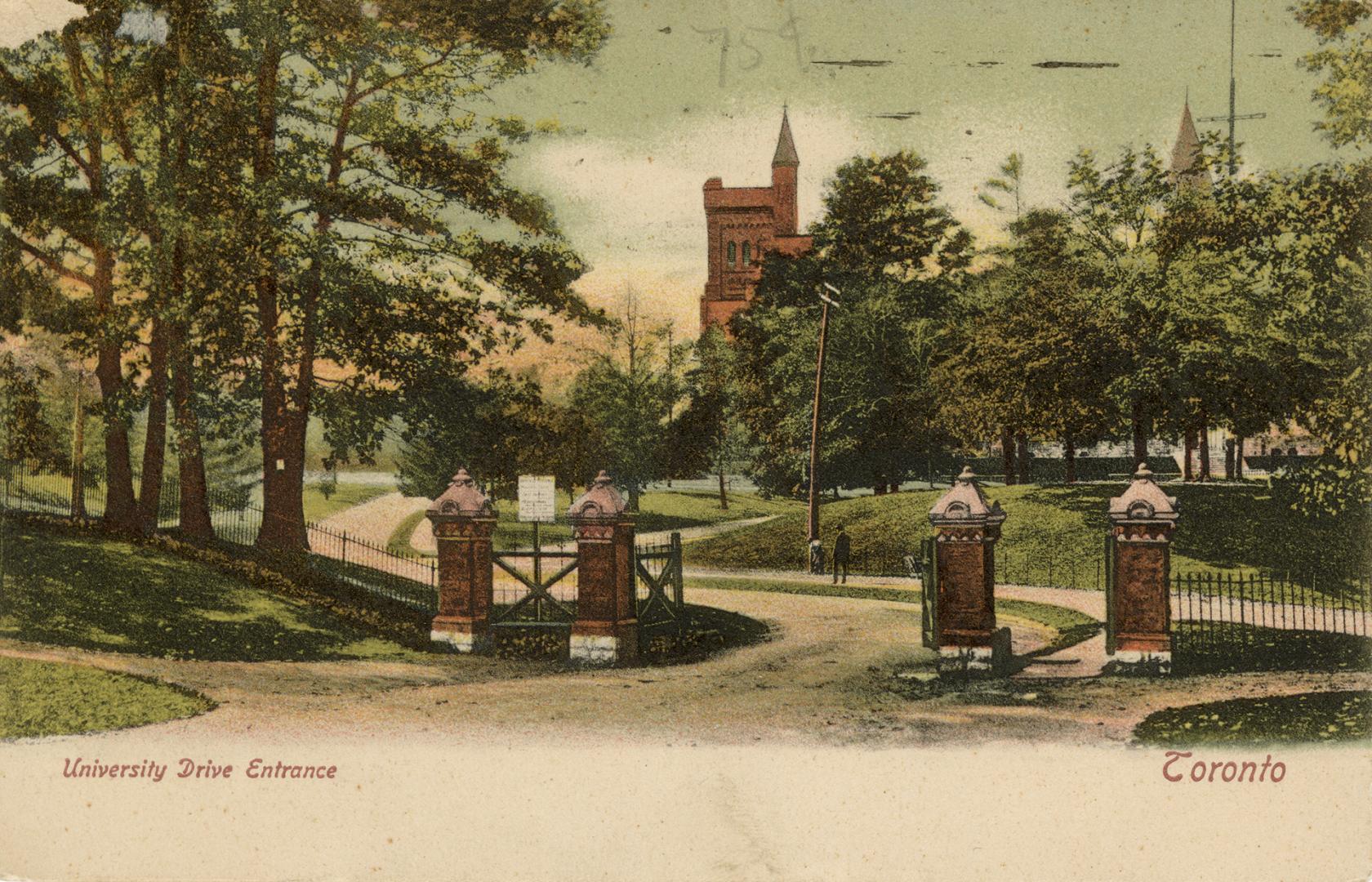 Brick gates on a roadway in front of trees and a large collegiate building.