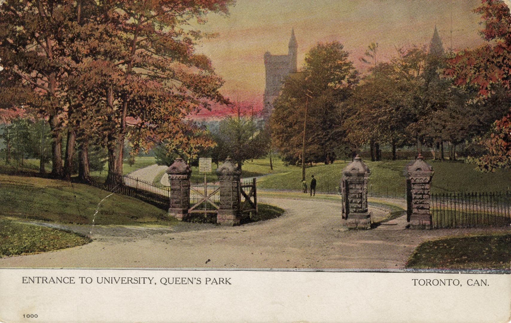 Brick gates on a roadway in front of trees and a large collegiate building with white border al…