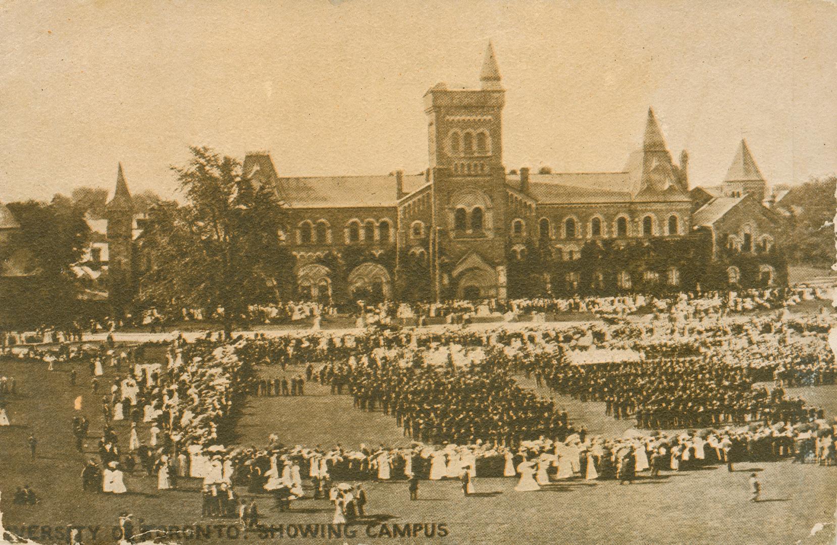 Sepia toned photograph of a very large stone building with many towers. Soldiers on parade in f…