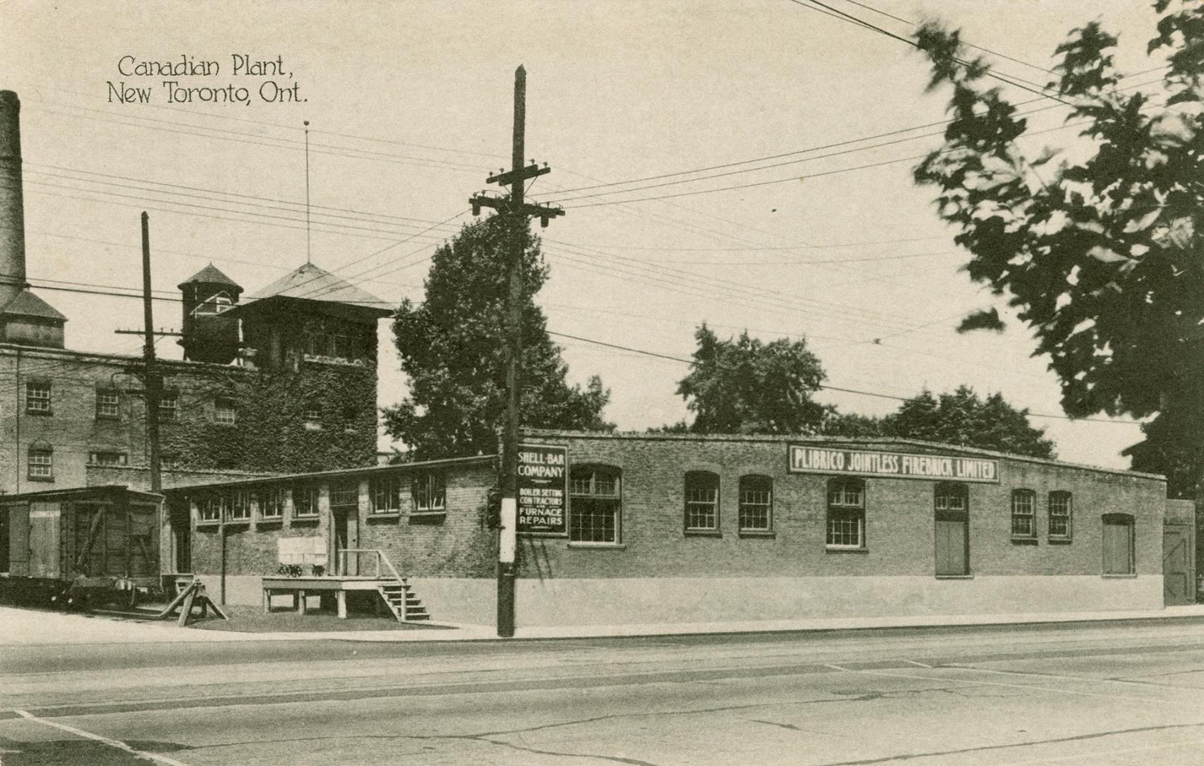 Black/white photo postcard depicting a warehouse building with the sign "Plibrico Jointless Fir…