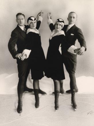 A photograph of four people on ice skates posing in a photography studio on what appears to be …