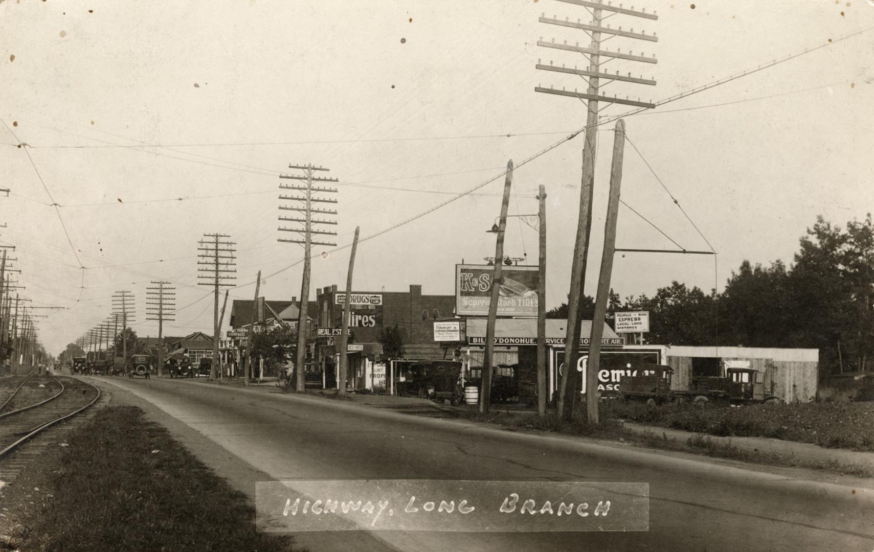 Sepia-toned photo postcard depicting Highway 2 looking east, with businesses on the right (sout…