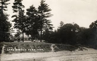 Black/white photo postcard depicting a beach and clubhouse with caption at the bottom stating, …