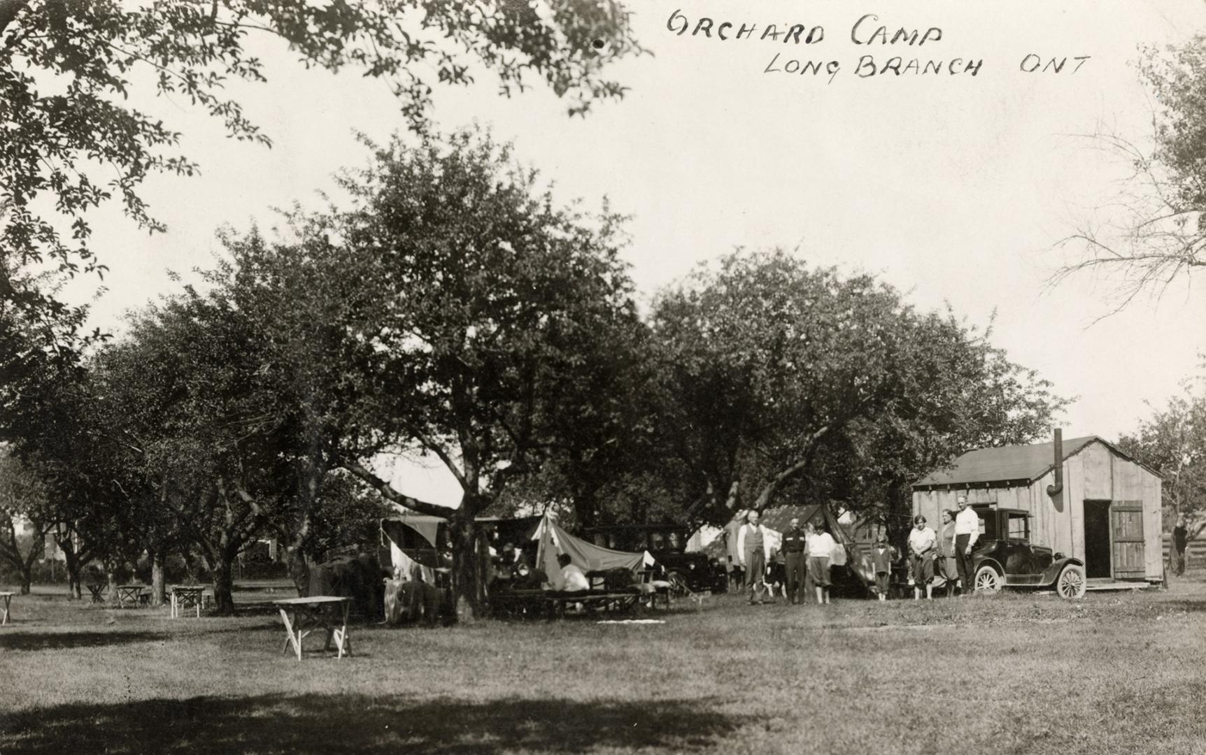 Black and white photo postcard depicting a tent and picnic tables in sight. A handwritten capti…