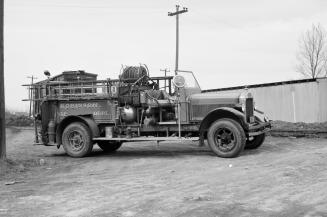 A photograph of a truck with water pumping equipment in its flatbed. The truck is parked on a d…