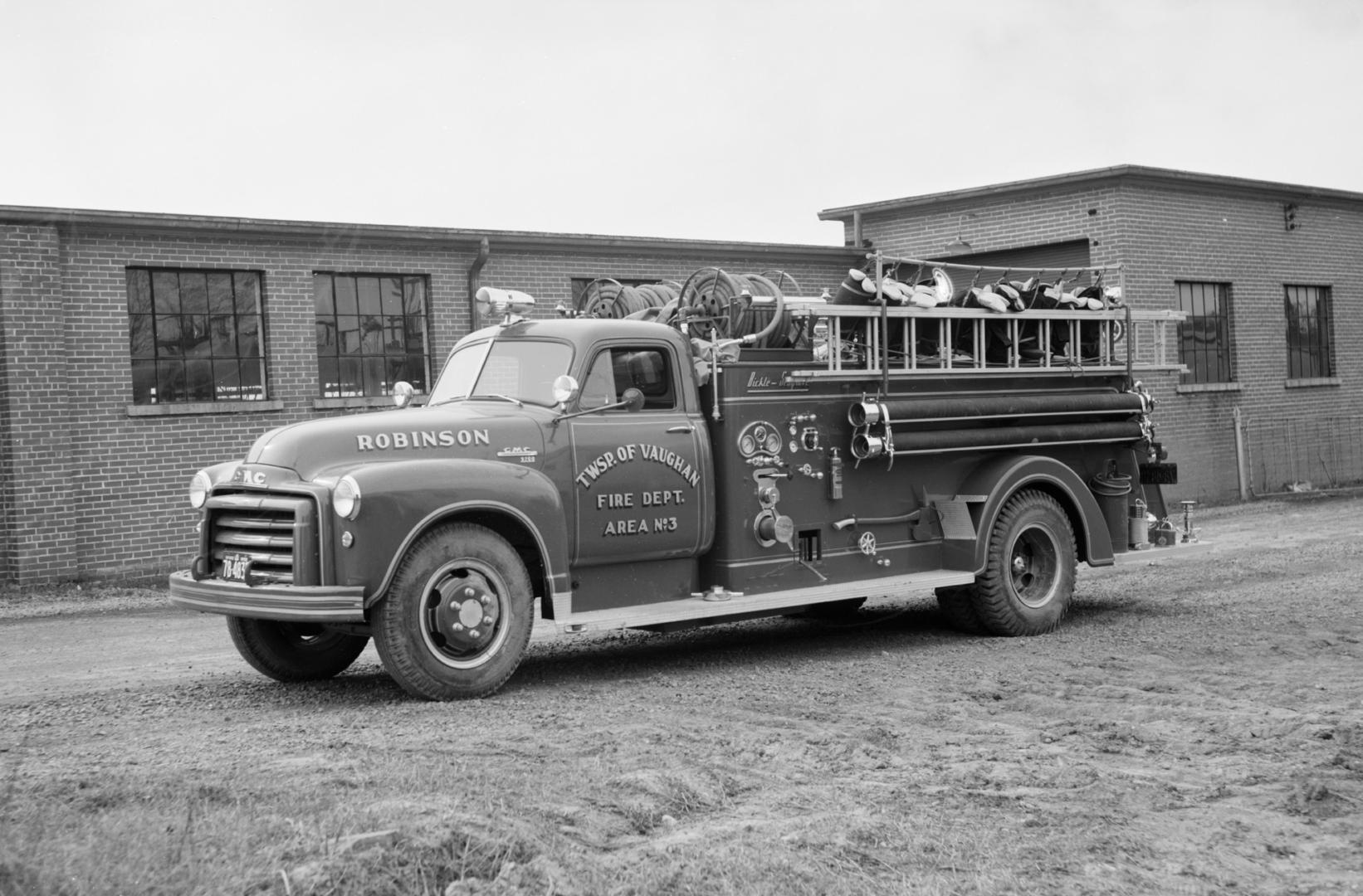 A photograph of a fire engine parked in front of a one store building. There is a ladder on the…