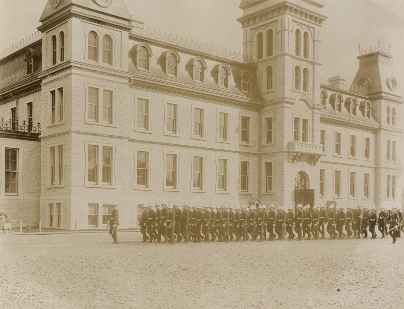 A photograph of a four-story building with windows evenly placed along both sides visible. Ther…