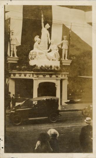 A photograph of a storefront with a number of large statues above an entrance or doorway. The s…