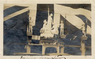 A photograph of the entranceway of a building, with statues depicting soldiers holding British  ...