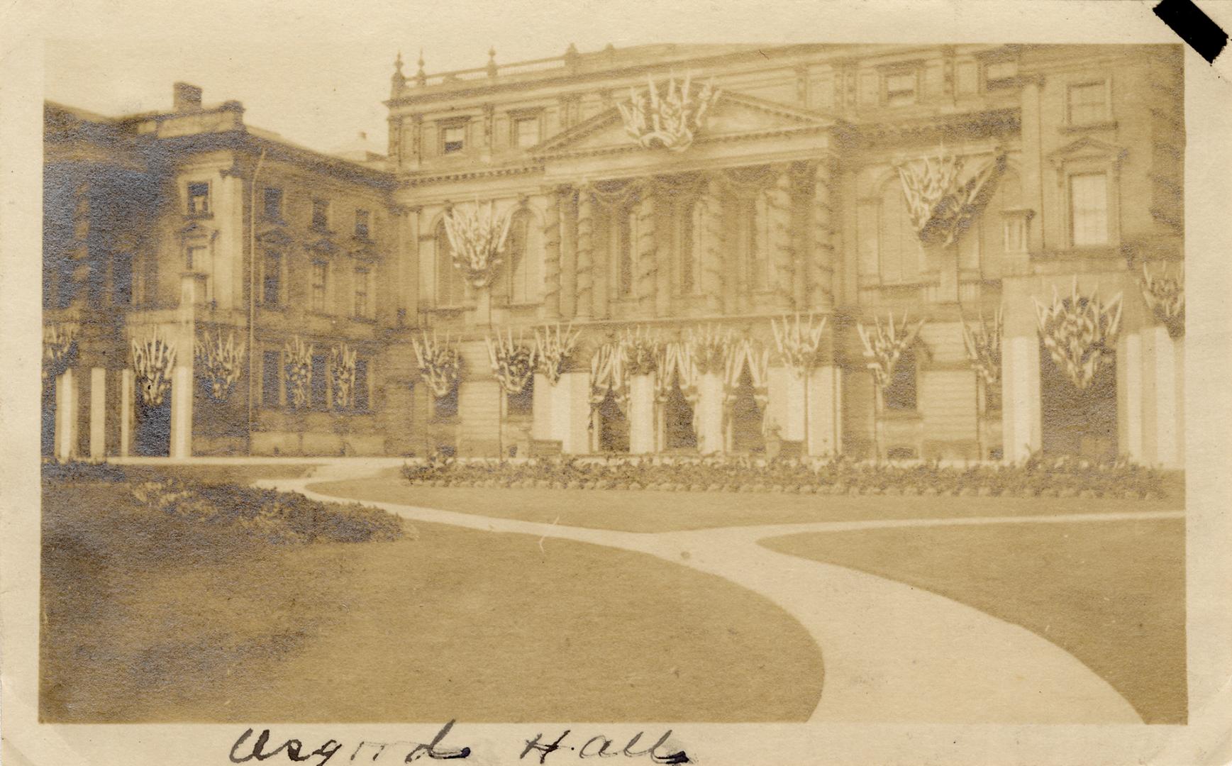 A photograph of a large hall with multiple arched entrances, columns above the front of the bui…