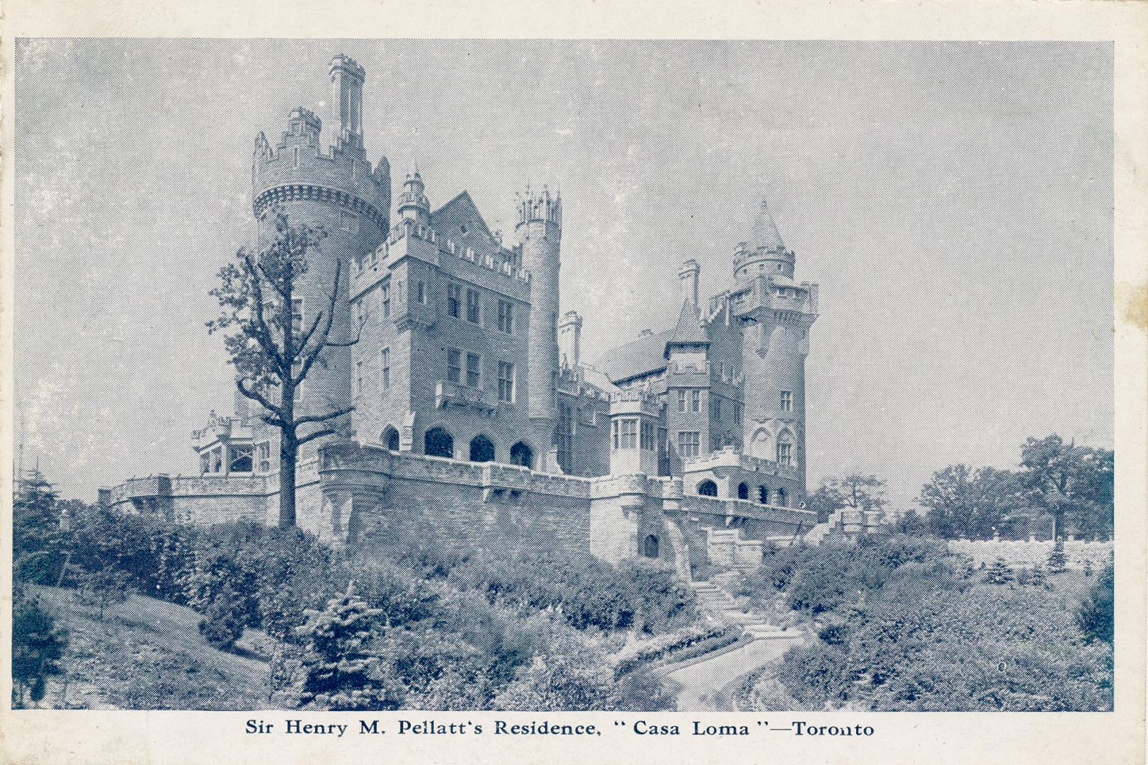 Black and white photograph of a castle with a stone wall in front of it.