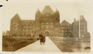 A photograph of two adults and one small child standing on a paved path leading towards the Leg…