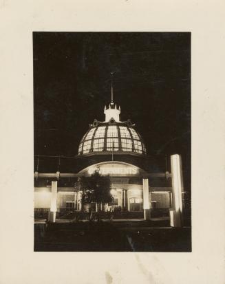 A photograph of a one story building with a dome partially constructed of glass. The photo is t…