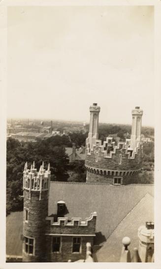 A photograph of a stone castle-like building, taken from a high vantage point on top of part of…