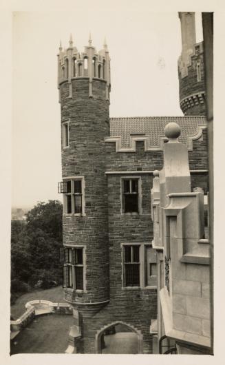 A photograph of a stone castle-like building, taken from a vantage point on a different part of…