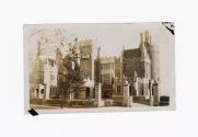 A photograph of a stone castle-like building, with round towers, spires, gates and ledges and l…