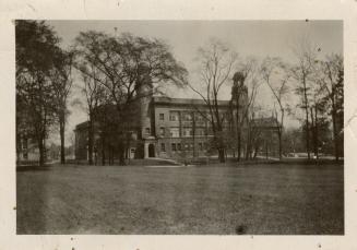 A photograph of a large three-story building with towers located at the front two corners. The  ...