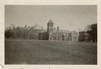 A photograph of a university campus, with a large stone building in the background and a large …