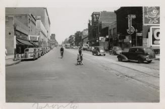 A photograph of a wide, paved city street with streetcar tracks in the middle of the street, ca…