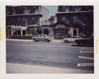 A photograph of a city street, with a paved road and sidewalks on both sides of the road. There ...