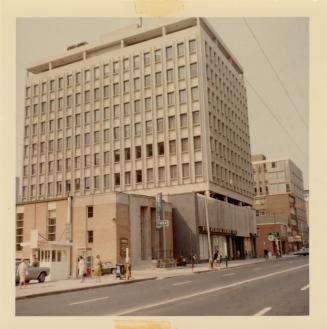 A photograph of a city street, with a row of buildings of varying heights on the right side of …