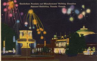 Colorized photograph of fireworks set off behind a large illuminated fountain. Night time pictu…