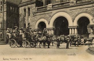 Black and white photograph of many tourists sitting in a horse drawn wagon in front of an arche…