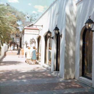 A photograph of a laneway or alley in a city, with a one story building on the right side and a…