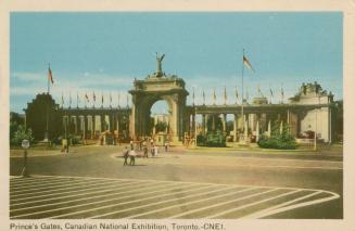 Color photograph of a large, neoclassical archway made of cement and stone. People are walking …