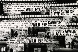 A multi-exposure photograph of the marquee and various posters in front of a movie theatre. The…