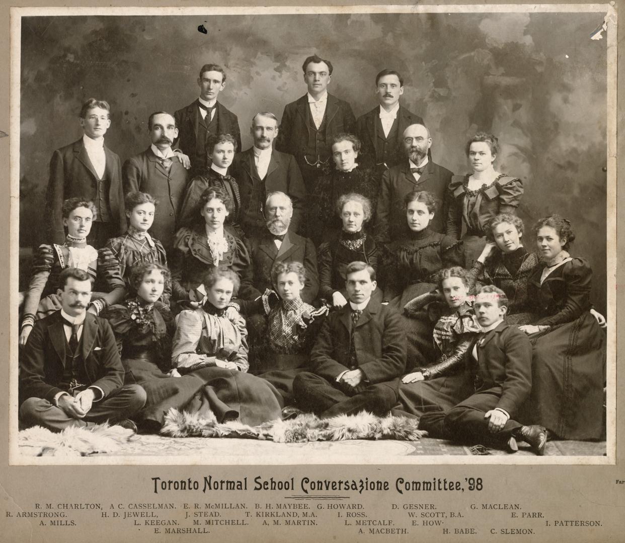 A photograph of a group of twenty-three people posing in a photography studio. There is a a fur…