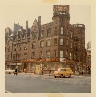 A photograph of a four story brick building, with signs on the roof and above the windows at st ...