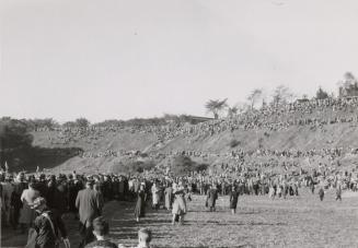 A photograph of a large crowd of people walking towards and gathered on a hillside surrounding …