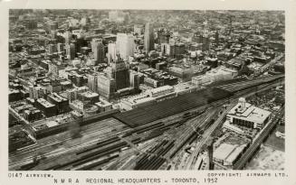 Black and white photograph of railway lines to the south of a large city. Taken from the air.