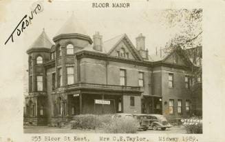 Black and white photograph of a huge, Victorian house with a sign "tourists" in front of it.