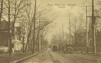 Sepia toned photograph of a streetcar and an automobile running along a city street with large …