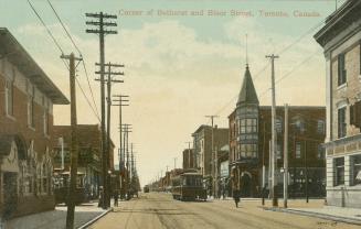 Colorized photograph of people and streetcars on a city street corner with three story building…