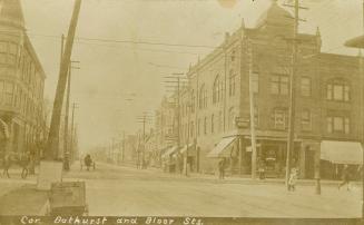 Black and white photograph of a city street with three story buildings on either side.