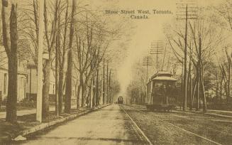 Sepia toned photograph of a streetcar and an automobile running along a city street with large …