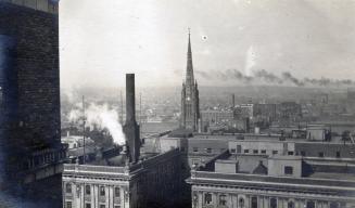 A photograph of a cityscape taken from a high vantage point. There are a number of multi-story …