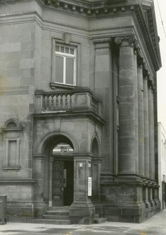 Picture of large stone library with pillars and corner entrance. 