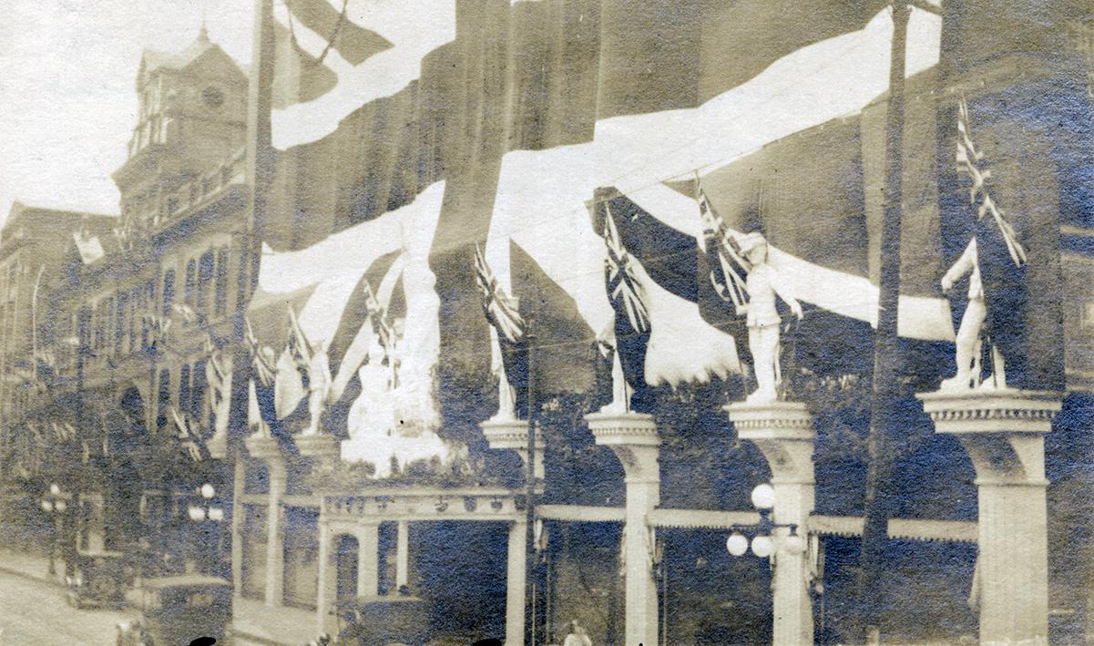 A photograph of storefront decorated with bunting and flags of the United Kingdom. The words "E…